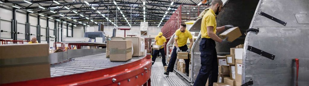 People loading packages onto conveyor belt