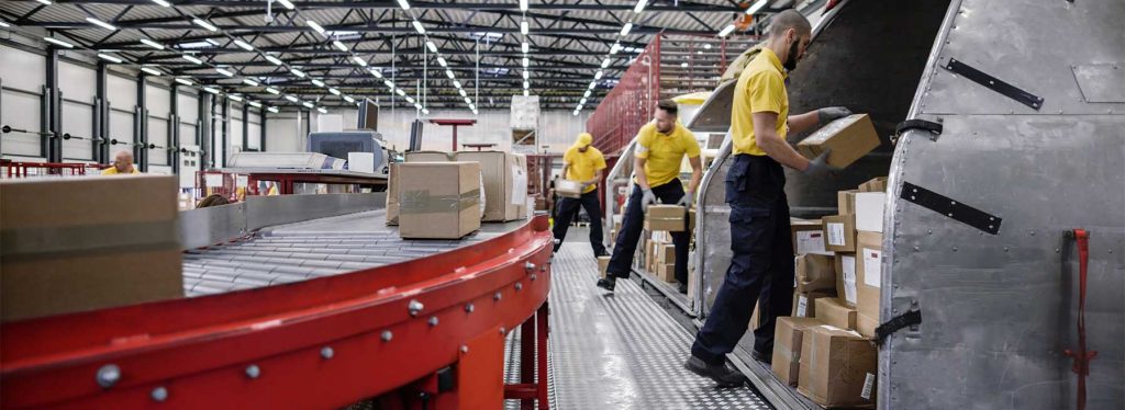 People loading packages onto conveyor belt